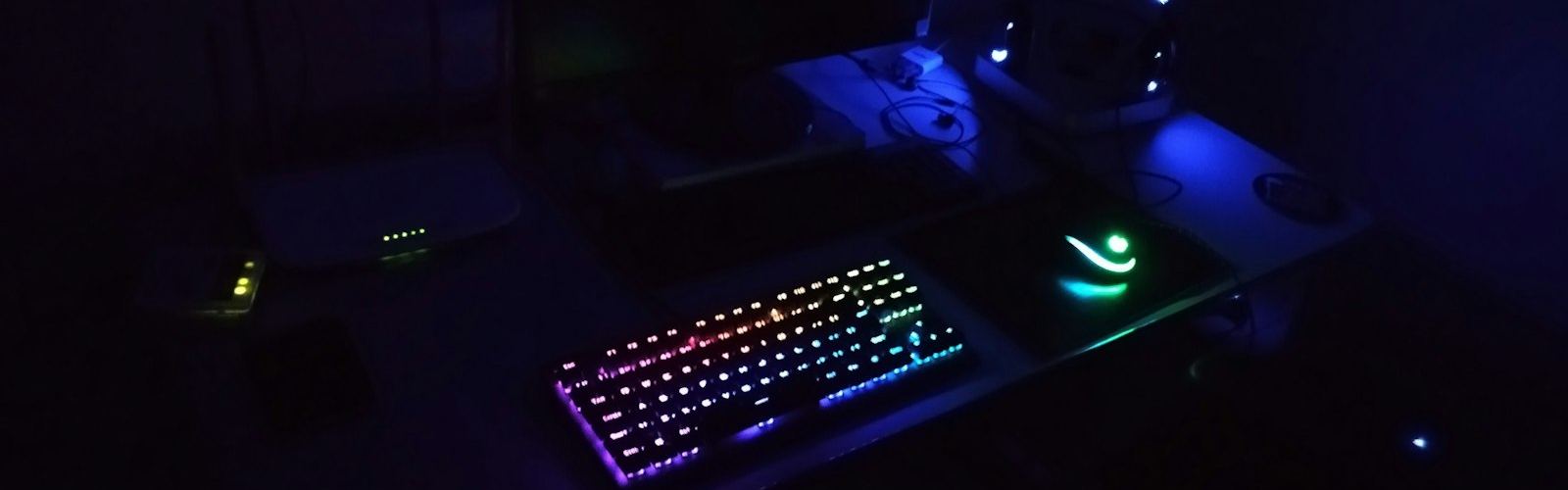 A dark desk with a backlit keyboard